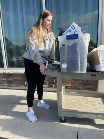 TTMT employee moving a bin of items on a cart